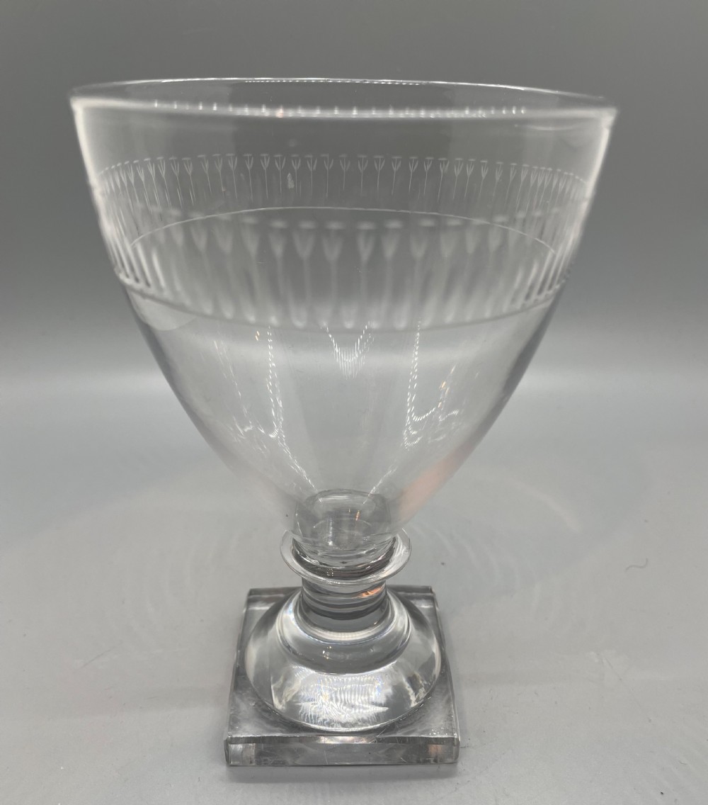 A clear Georgian glass rummer goblet featuring an etched rim band and a square pedestal base. View III