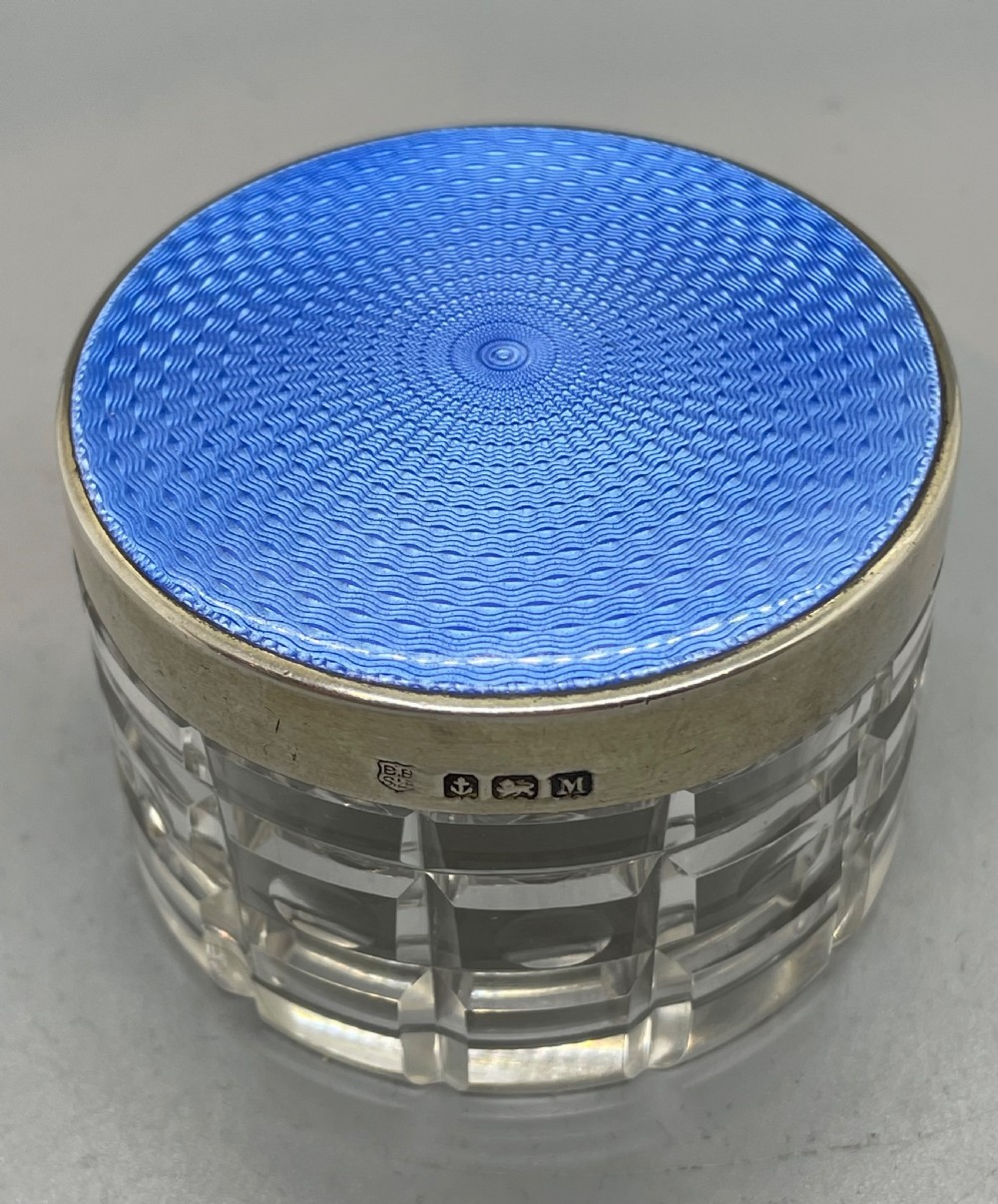 An Art Deco round clear glass vanity jar topped with a sterling silver rim and a blue engine-turned guilloche enamel lid. View V