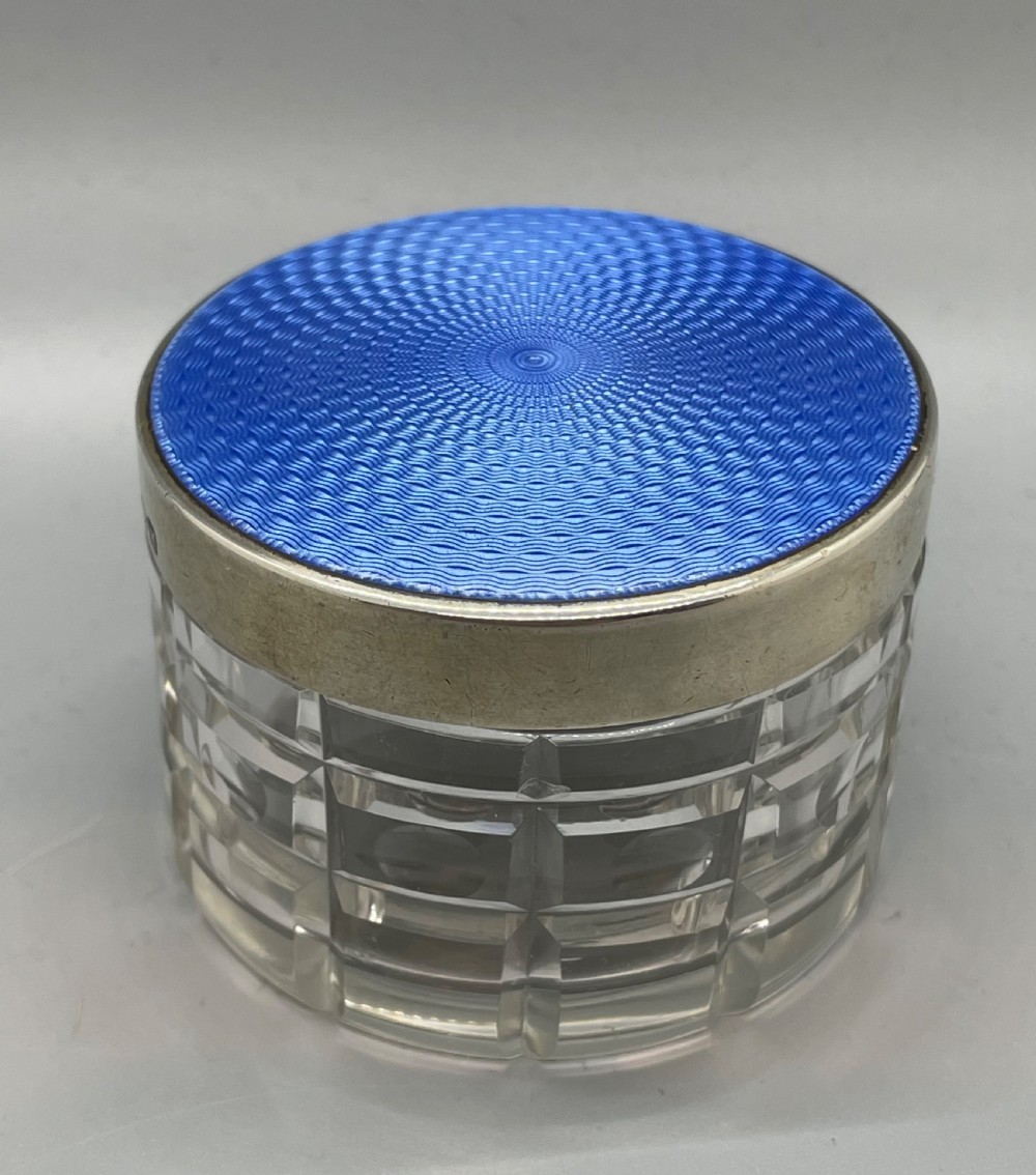 An Art Deco round clear glass vanity jar topped with a sterling silver rim and a blue engine-turned guilloche enamel lid. View VII