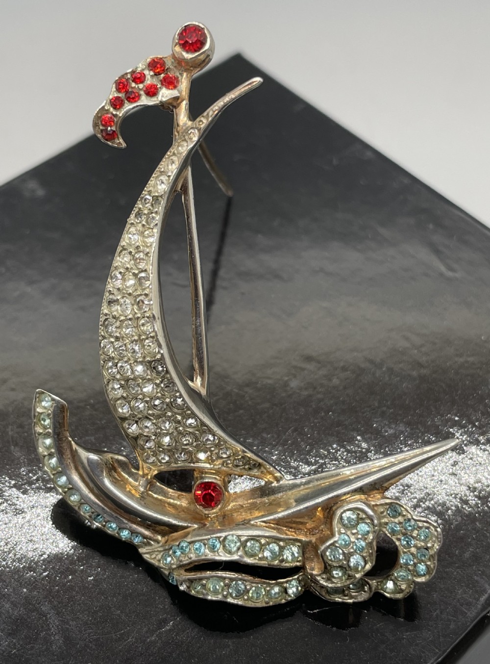 A 1940s sterling silver gilt brooch in the shape of a sailing yacht set with clear, light blue, and red rhinestones. View II