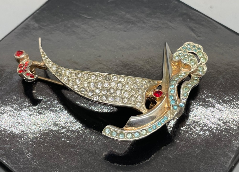 A 1940s sterling silver gilt brooch in the shape of a sailing yacht set with clear, light blue, and red rhinestones. View V