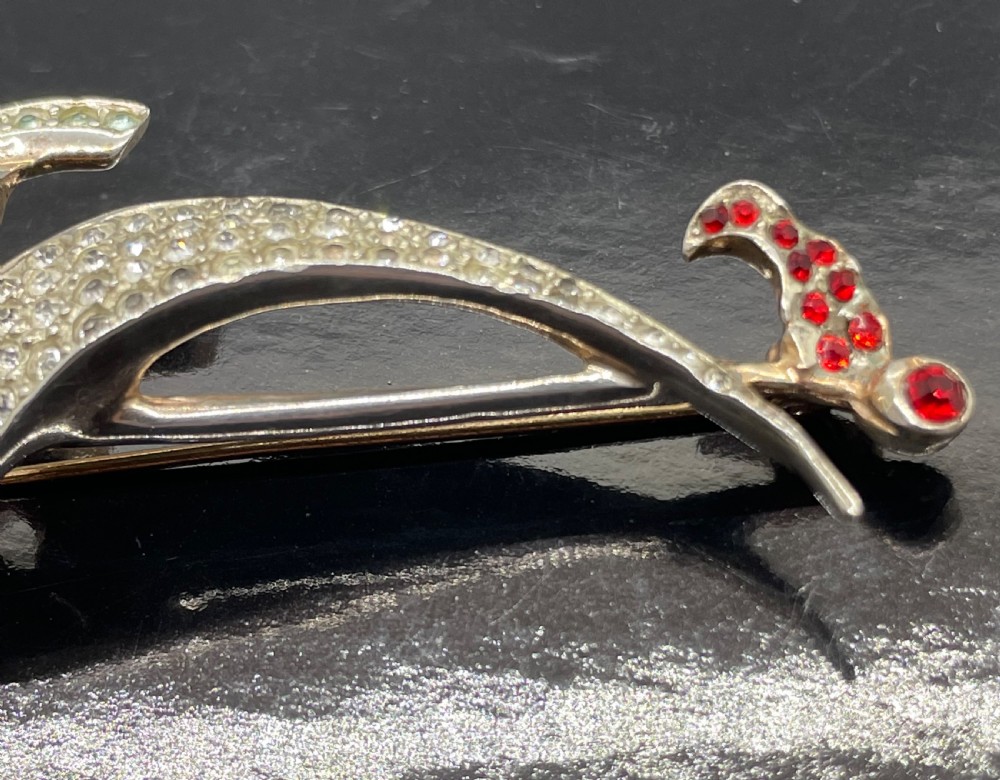 A 1940s sterling silver gilt brooch in the shape of a sailing yacht set with clear, light blue, and red rhinestones. View X