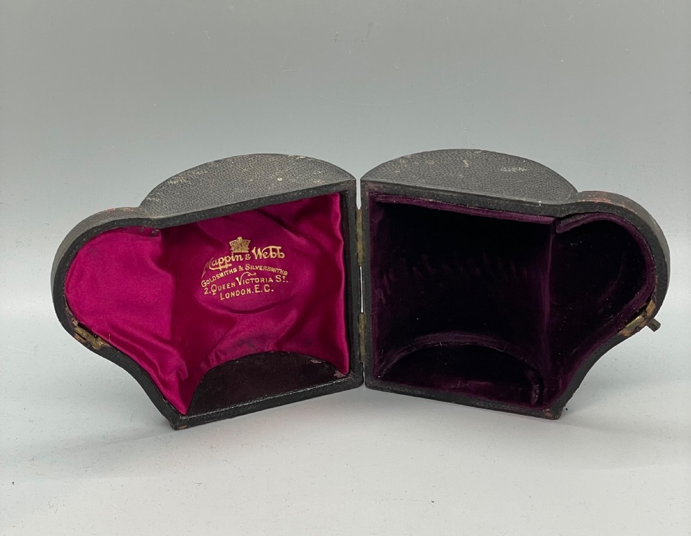 An antique sterling silver christening mug featuring floral engravings and beaded edges, placed beside its original fitted leather case lined with magenta velvet. View XII