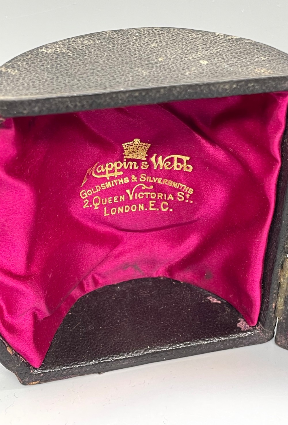 An antique sterling silver christening mug featuring floral engravings and beaded edges, placed beside its original fitted leather case lined with magenta velvet. View XIII