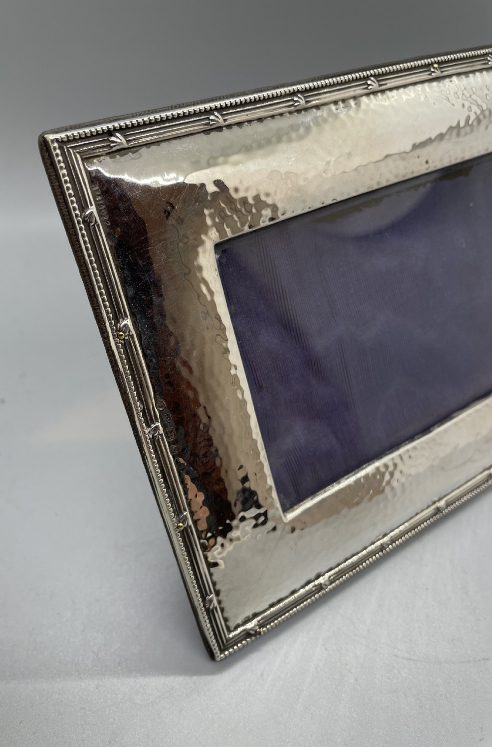 A horizontal rectangular Edwardian sterling silver photo frame featuring a hand-hammered texture and a narrow beaded rim. View VI