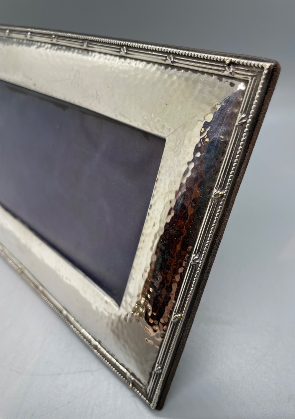 A horizontal rectangular Edwardian sterling silver photo frame featuring a hand-hammered texture and a narrow beaded rim. View IX
