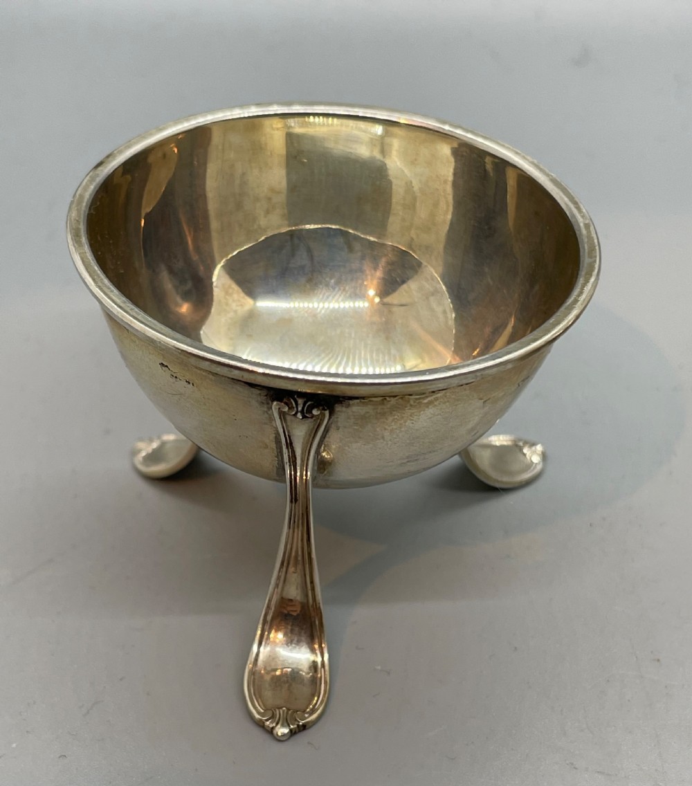 A Danish Art Deco silver tea strainer with a pierced bowl design and a smooth flat handle resting on a tripod stand. View IV