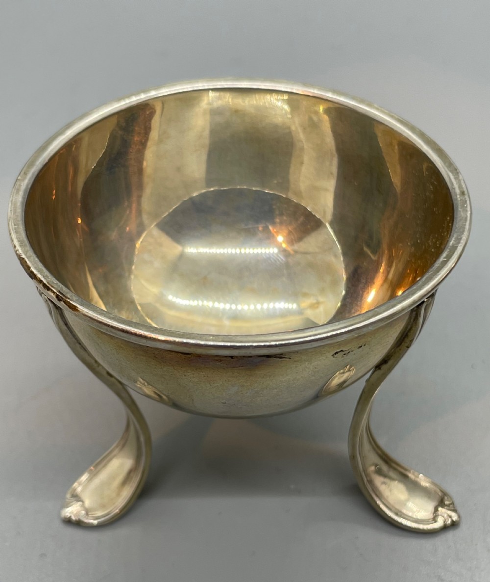 A Danish Art Deco silver tea strainer with a pierced bowl design and a smooth flat handle resting on a tripod stand. View V