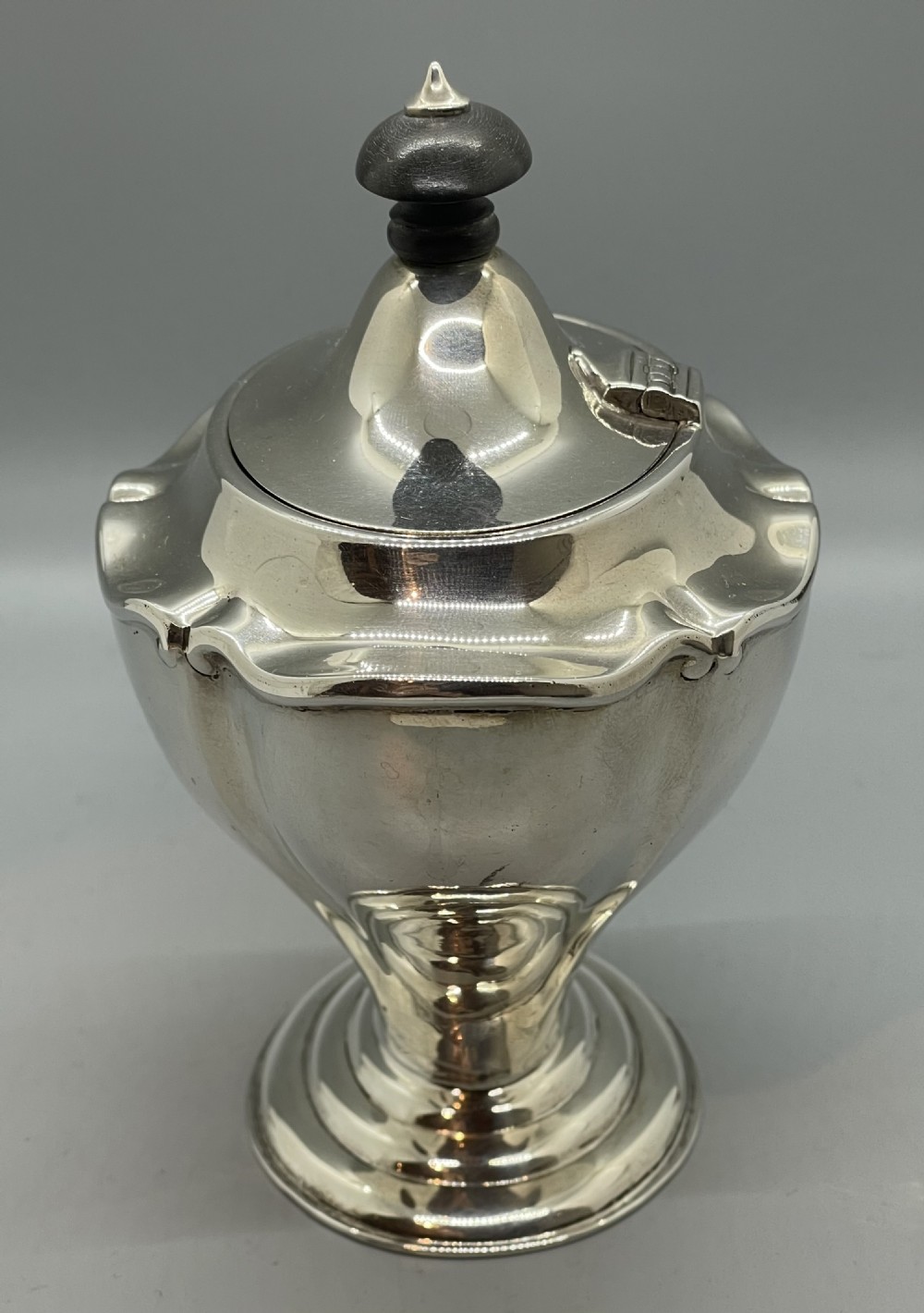 A George V sterling silver tea caddy with a lobed pedestal body, fitted lid, and a dark wooden finial. View II