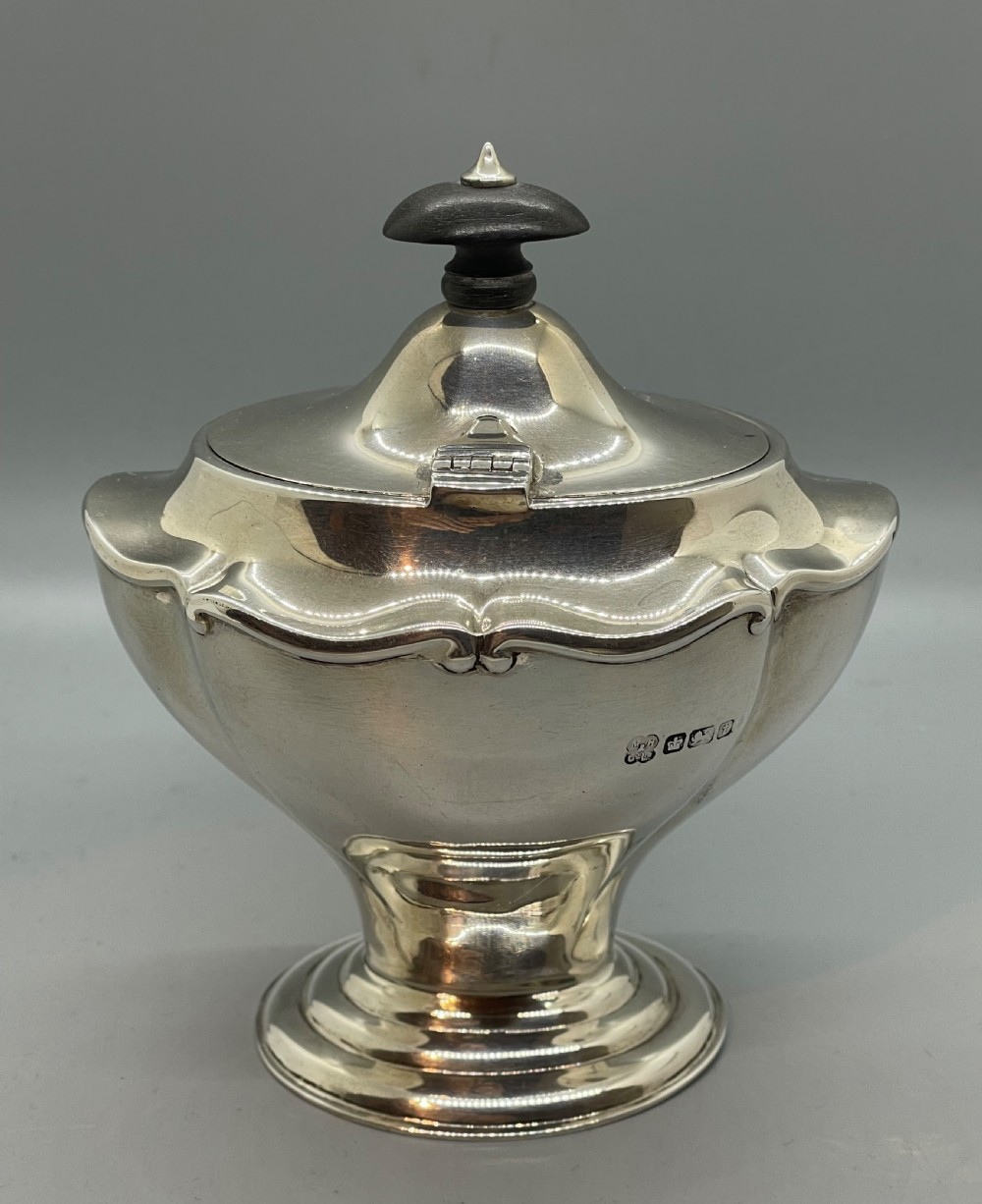 A George V sterling silver tea caddy with a lobed pedestal body, fitted lid, and a dark wooden finial. View III