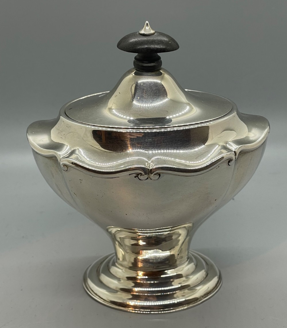 A George V sterling silver tea caddy with a lobed pedestal body, fitted lid, and a dark wooden finial. View V