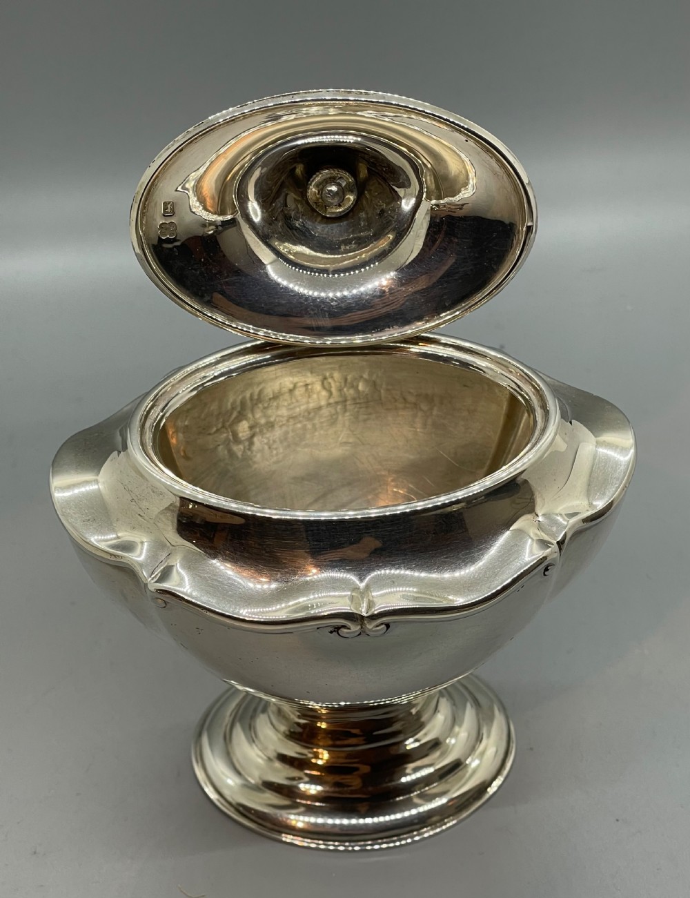 A George V sterling silver tea caddy with a lobed pedestal body, fitted lid, and a dark wooden finial. View VI