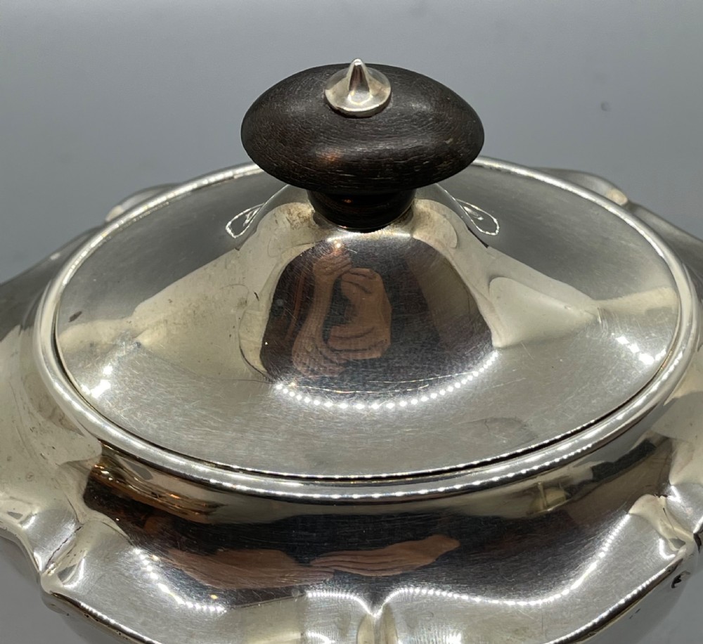 A George V sterling silver tea caddy with a lobed pedestal body, fitted lid, and a dark wooden finial. View IX