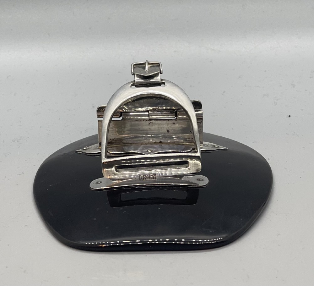 An Edwardian sterling silver letter clip styled as an equestrian stirrup on a smooth dark tortoiseshell base.