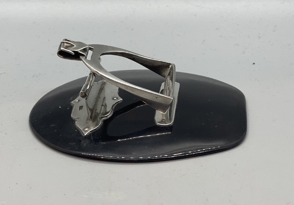 An Edwardian sterling silver letter clip styled as an equestrian stirrup on a smooth dark tortoiseshell base. View III
