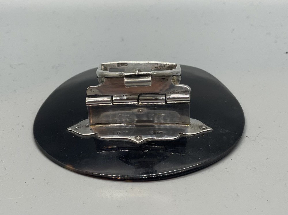 An Edwardian sterling silver letter clip styled as an equestrian stirrup on a smooth dark tortoiseshell base. View IV