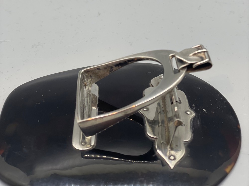 An Edwardian sterling silver letter clip styled as an equestrian stirrup on a smooth dark tortoiseshell base. View VII