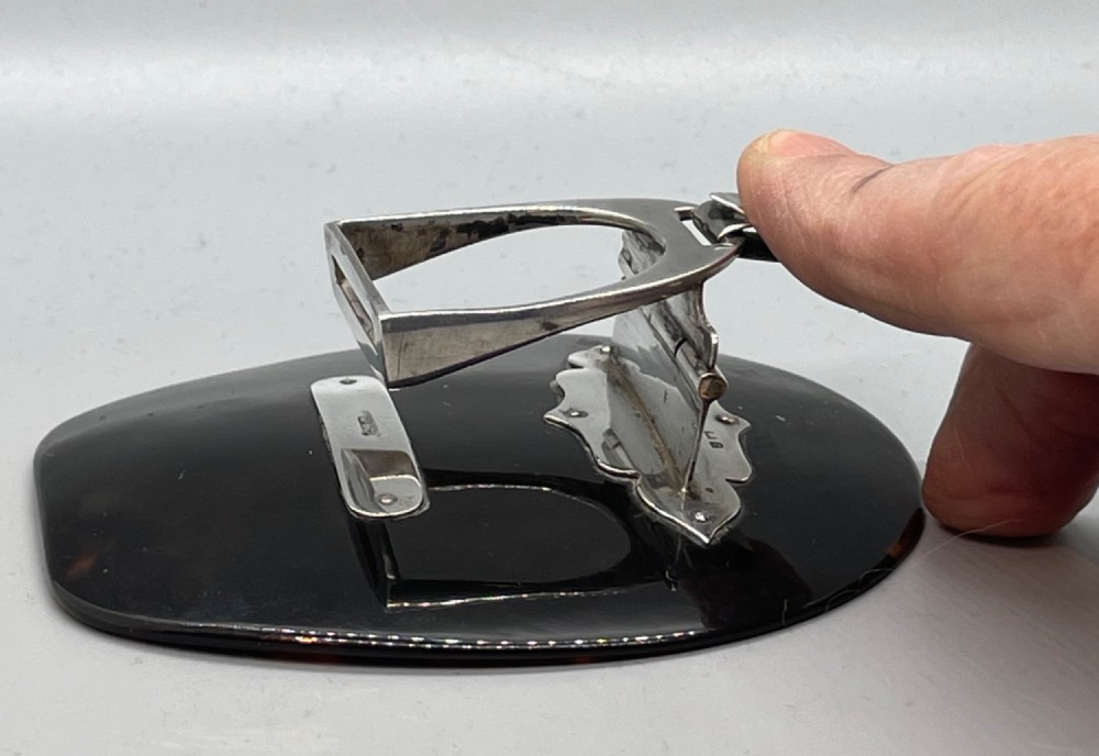 An Edwardian sterling silver letter clip styled as an equestrian stirrup on a smooth dark tortoiseshell base. View XIII