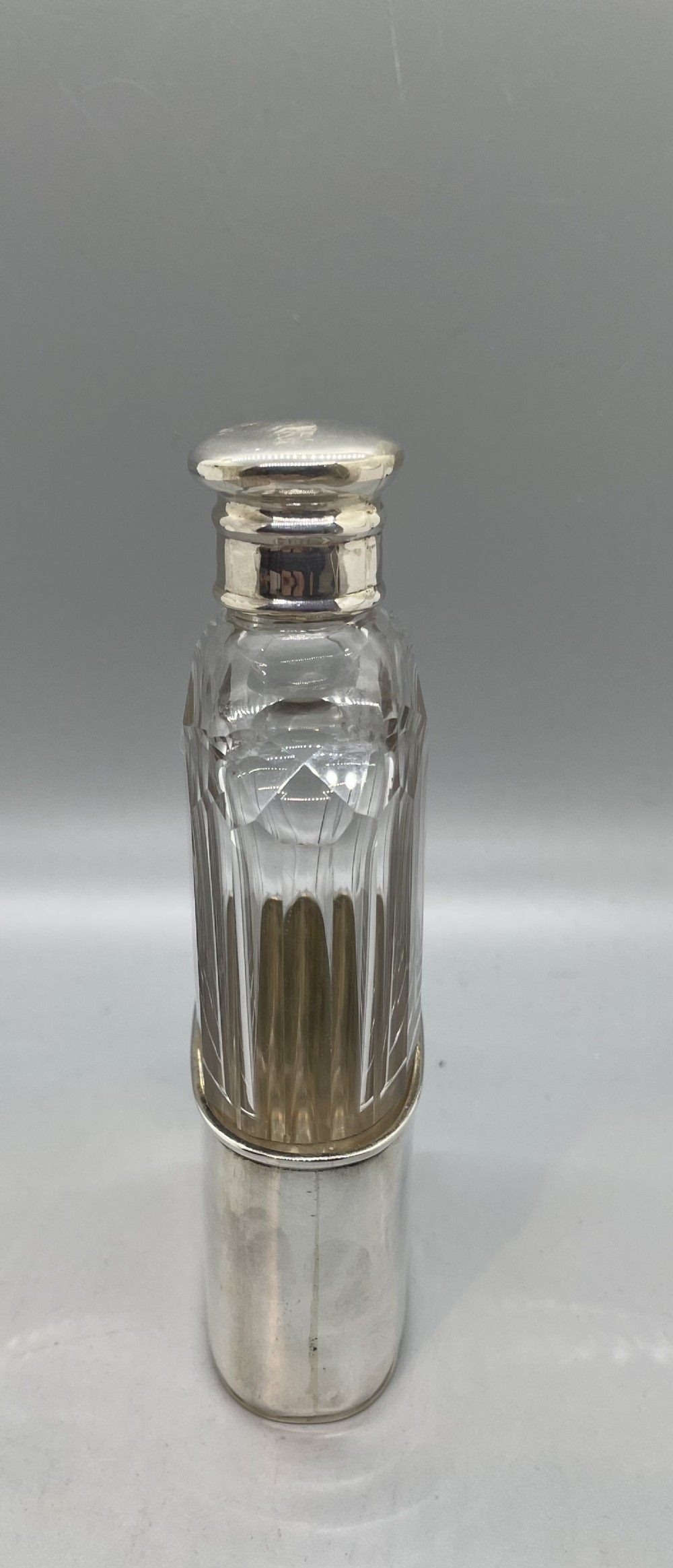 A Victorian glass spirit flask featuring a faceted clear glass upper section, a silver collar with cap, and a detachable silver base cup. View III