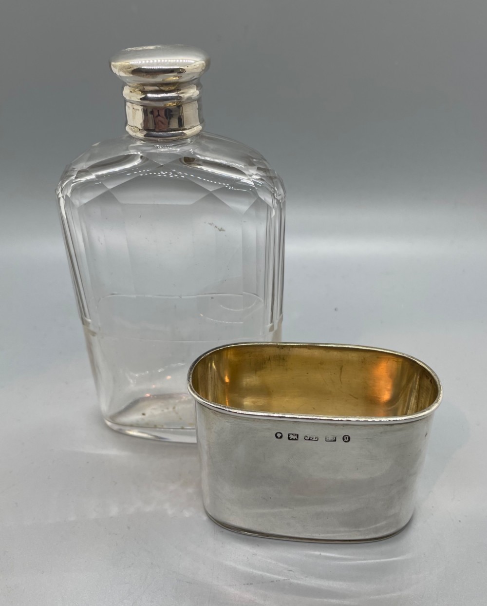 A Victorian glass spirit flask featuring a faceted clear glass upper section, a silver collar with cap, and a detachable silver base cup. View IV