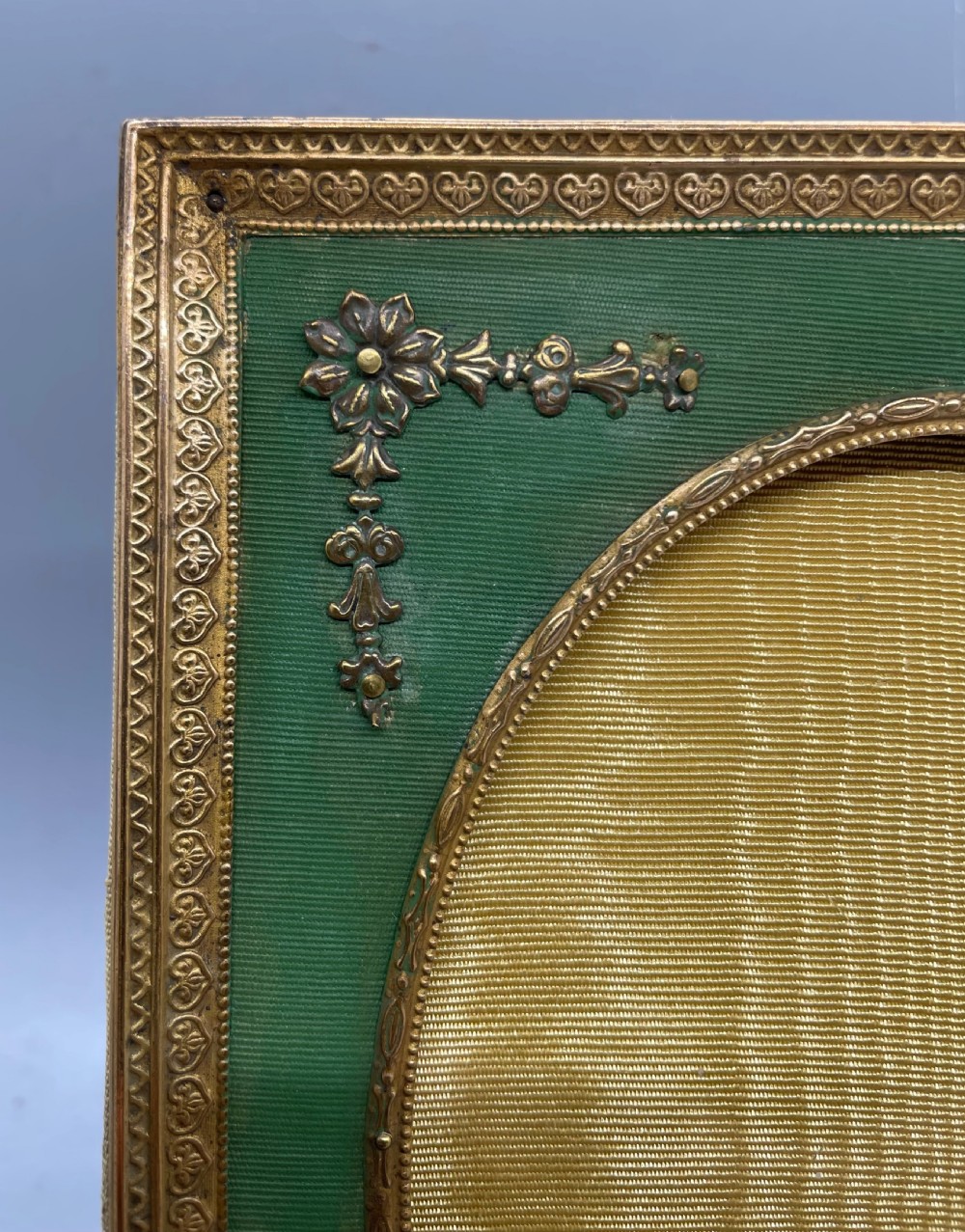 An Edwardian rectangular metal photo frame with a green fabric mount, gilt floral corner appliques, and an oval aperture. View III
