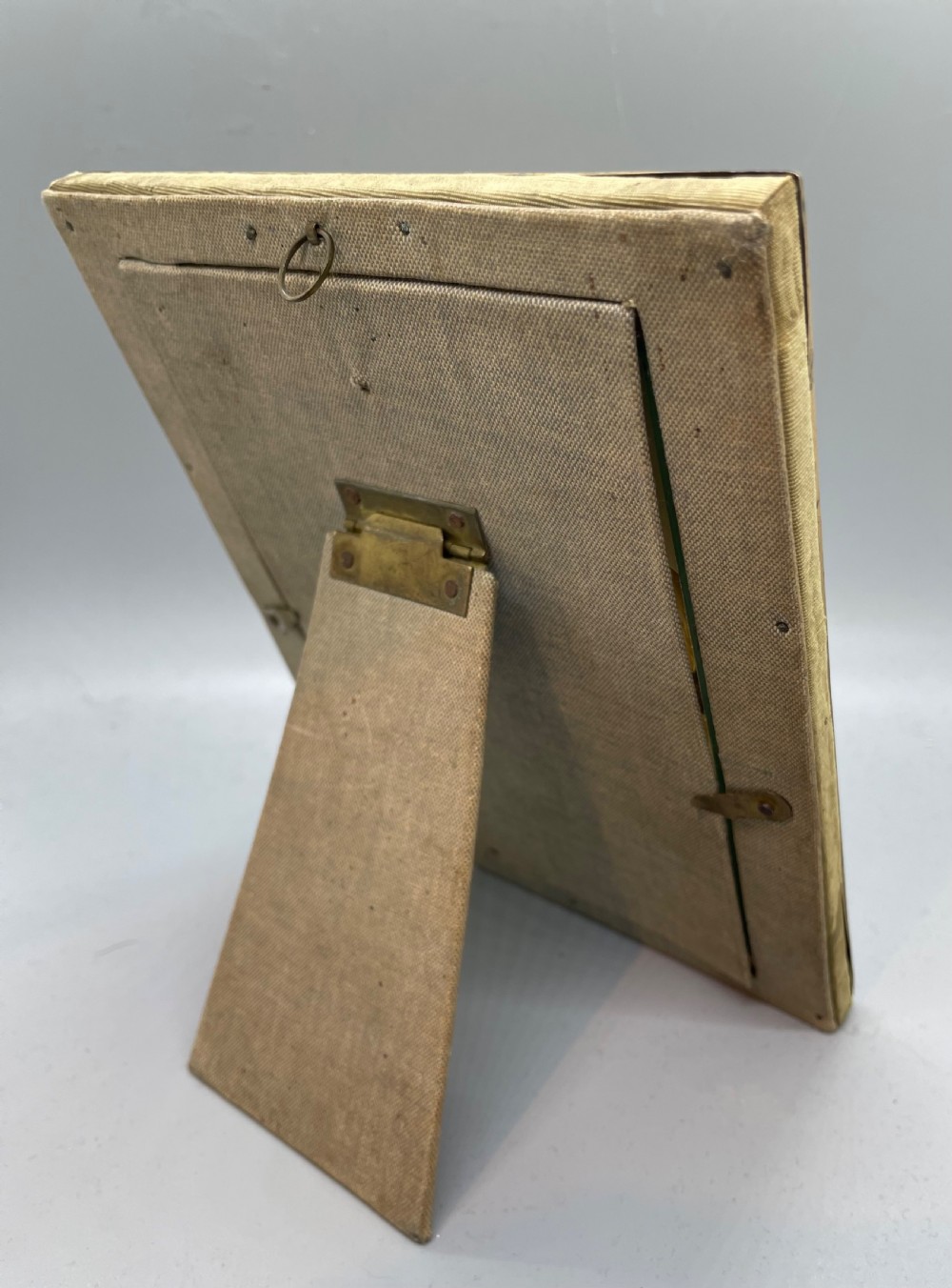 An Edwardian rectangular metal photo frame with a green fabric mount, gilt floral corner appliques, and an oval aperture. View IX