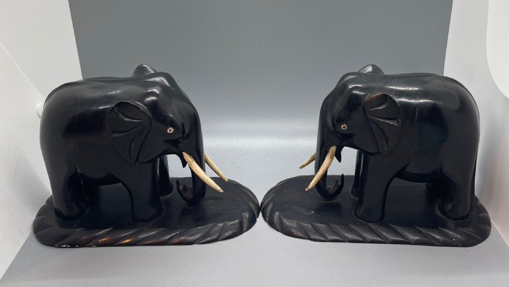 A pair of hand-carved dark wood elephant bookends from the Art Deco period, featuring light-coloured inlaid tusks and carved rope-twist edges on the bases. View II