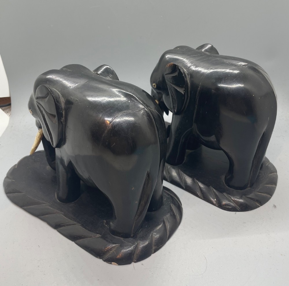 A pair of hand-carved dark wood elephant bookends from the Art Deco period, featuring light-coloured inlaid tusks and carved rope-twist edges on the bases. View IV