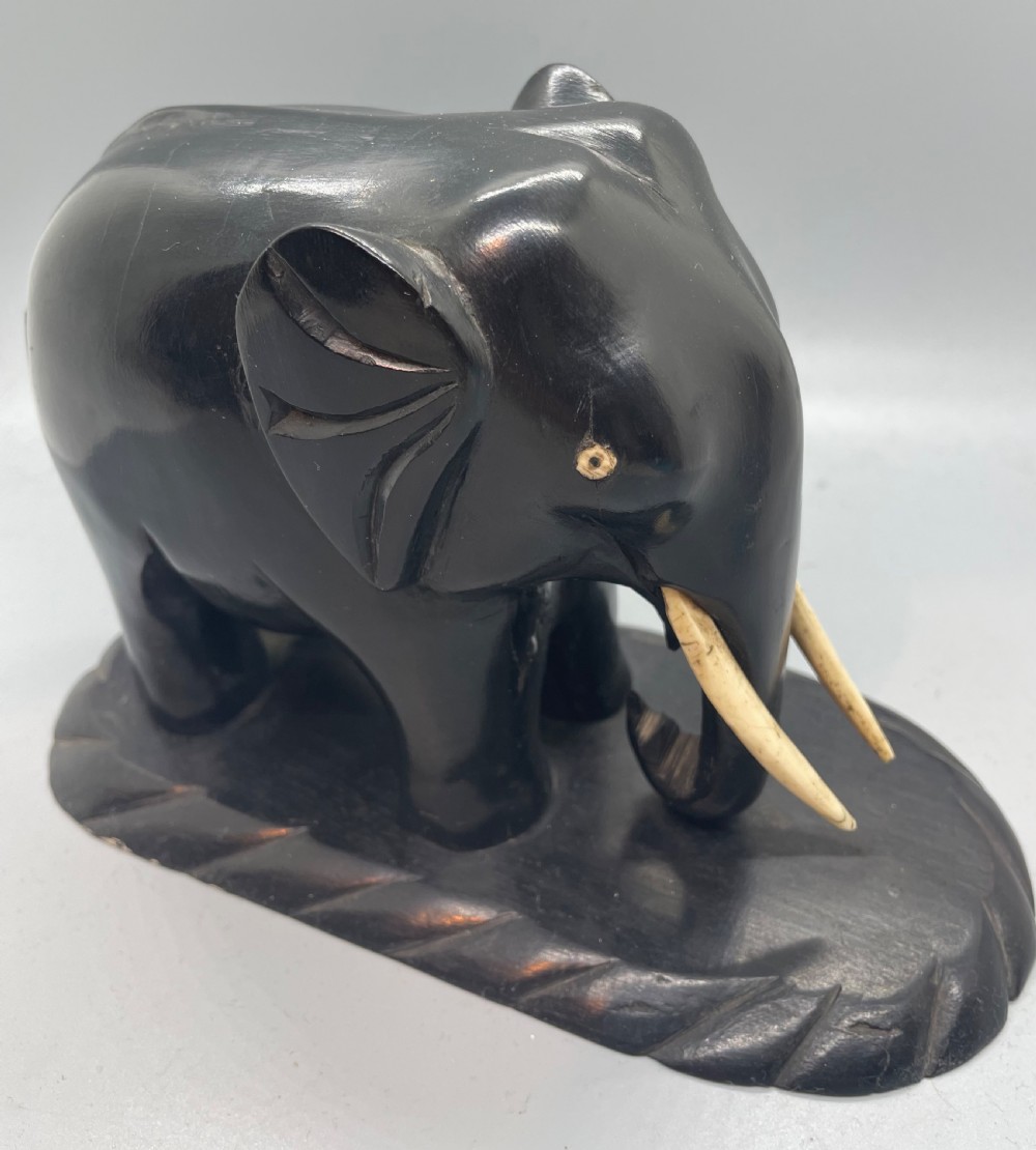 A pair of hand-carved dark wood elephant bookends from the Art Deco period, featuring light-coloured inlaid tusks and carved rope-twist edges on the bases. View VI