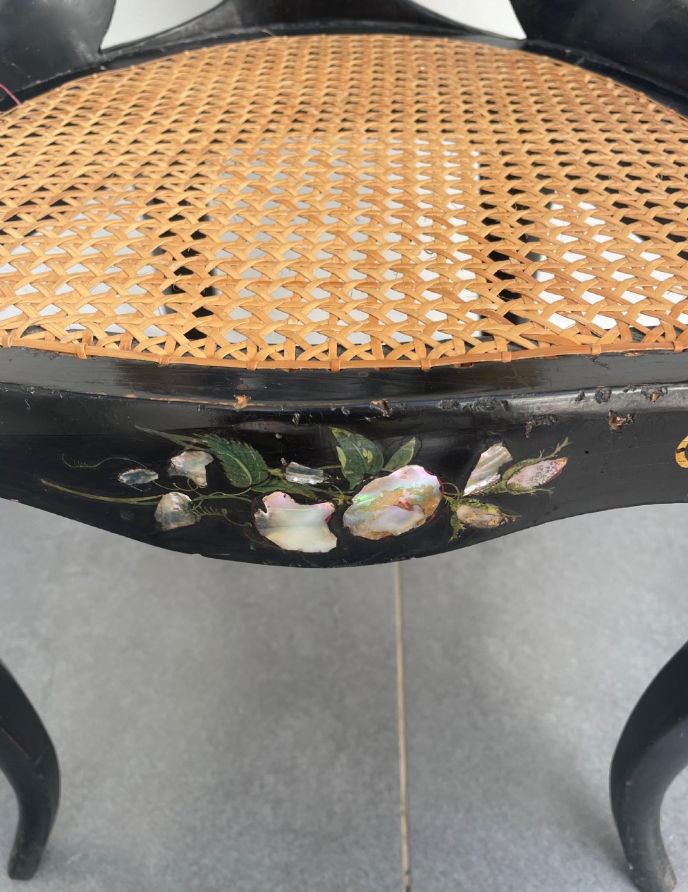 A Victorian ebonised side chair featuring floral mother-of-pearl inlays, gold leaf scrollwork decoration, a shaped back rest, cabriole front legs, and a woven cane seat. View V