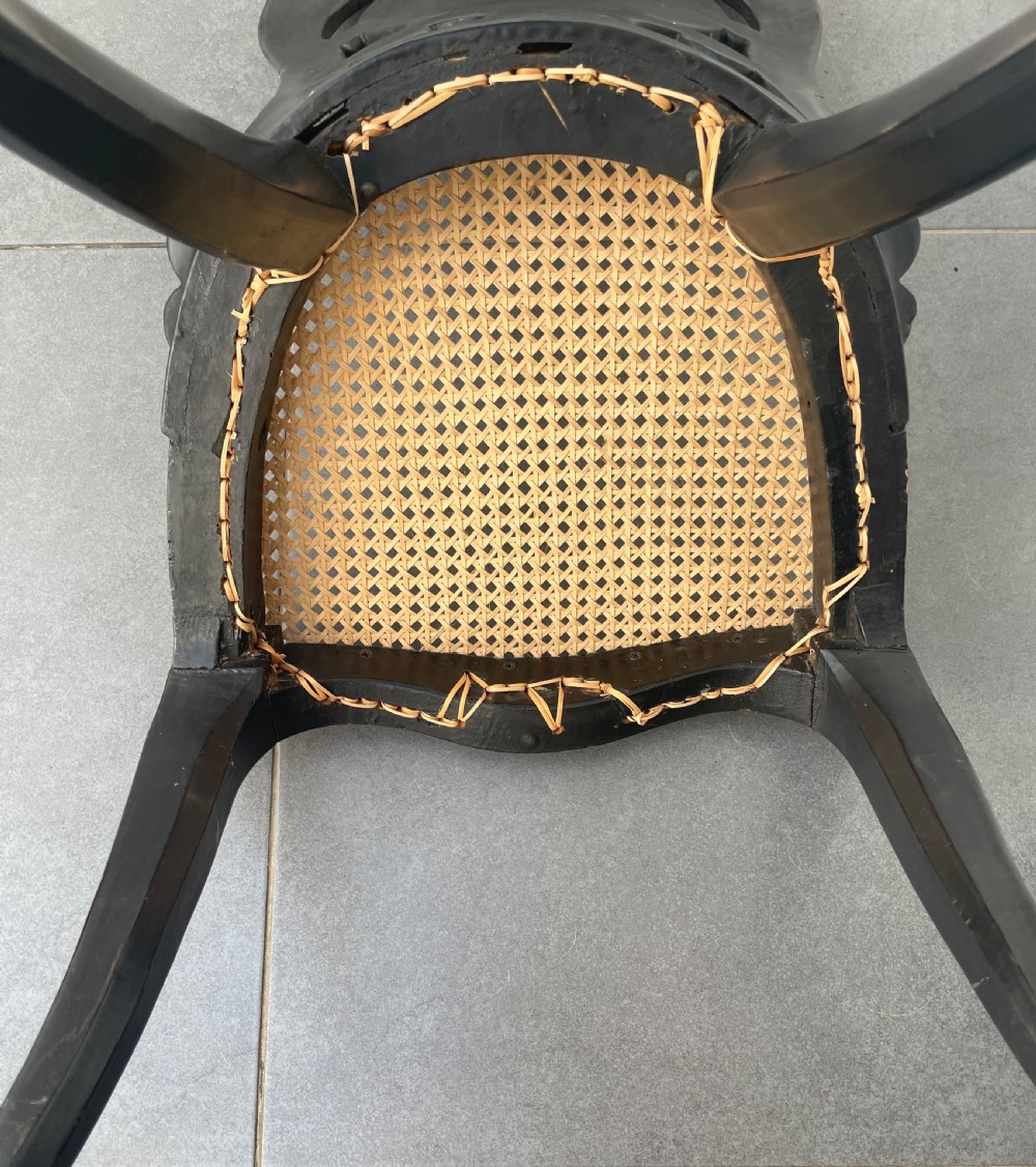 A Victorian ebonised side chair featuring floral mother-of-pearl inlays, gold leaf scrollwork decoration, a shaped back rest, cabriole front legs, and a woven cane seat. View IX