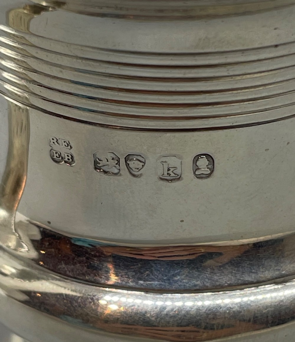 A George IV sterling silver mug featuring horizontal reeded decoration, a leaf-scrolled handle, a molded pedestal foot, and a gold-gilded interior. View X