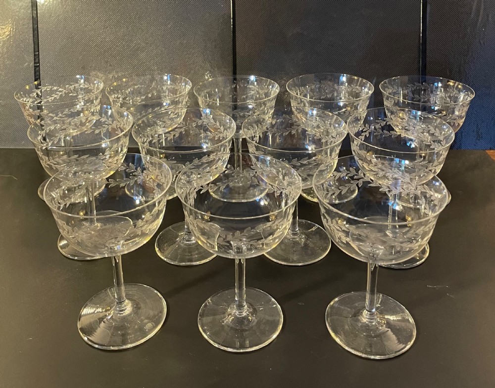 A set of twelve clear Edwardian glass champagne coupes featuring acid-etched laurel leaf garlands around the bowls. View II