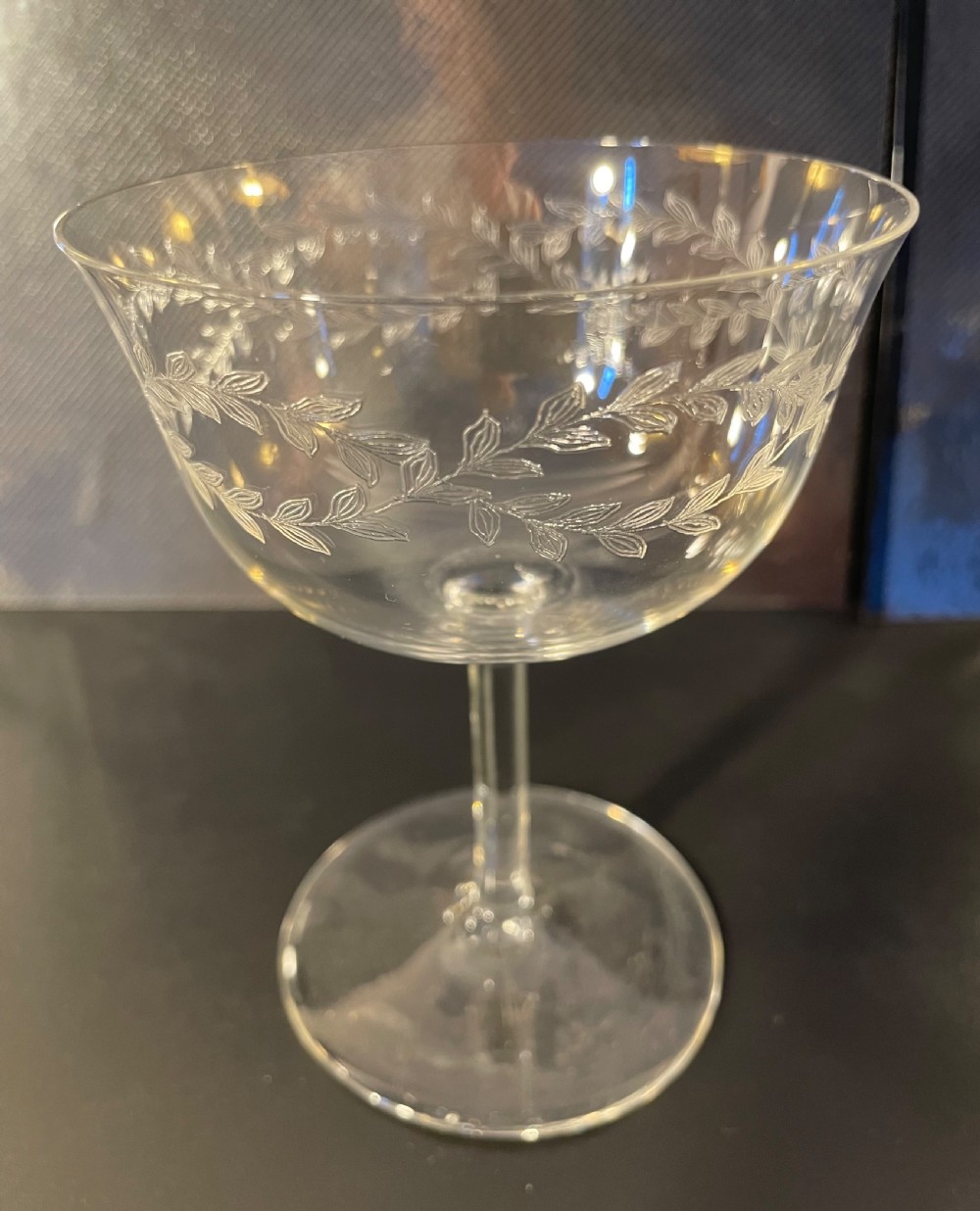 A set of twelve clear Edwardian glass champagne coupes featuring acid-etched laurel leaf garlands around the bowls. View VII