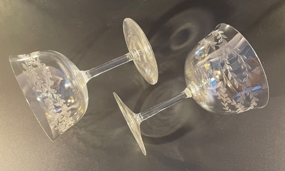 A set of twelve clear Edwardian glass champagne coupes featuring acid-etched laurel leaf garlands around the bowls. View IX