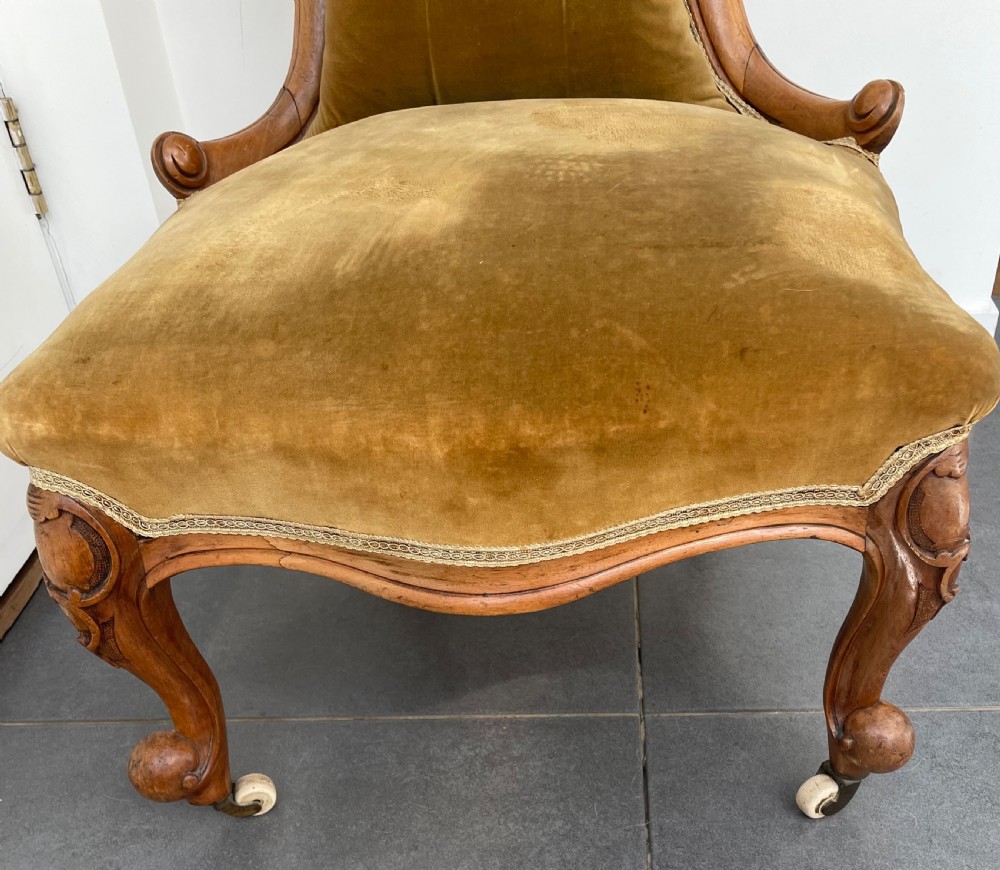 A Victorian walnut occasional chair featuring a spoon-shaped button-backed backrest upholstered in mustard velvet, supported by carved cabriole legs with ceramic castors. View II