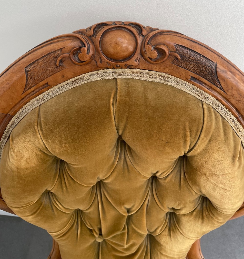 A Victorian walnut occasional chair featuring a spoon-shaped button-backed backrest upholstered in mustard velvet, supported by carved cabriole legs with ceramic castors. View VIII