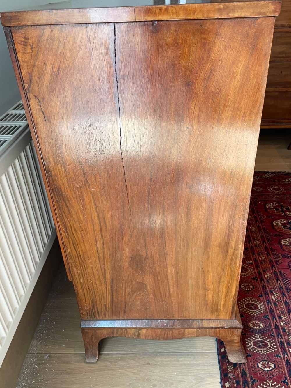 A George V walnut chest of drawers featuring four drawers with figured veneer fronts, brass drop handles, and bracket feet. View VII