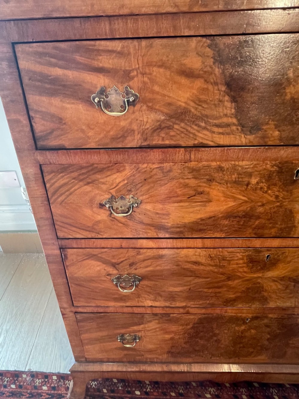 A George V walnut chest of drawers featuring four drawers with figured veneer fronts, brass drop handles, and bracket feet. View X