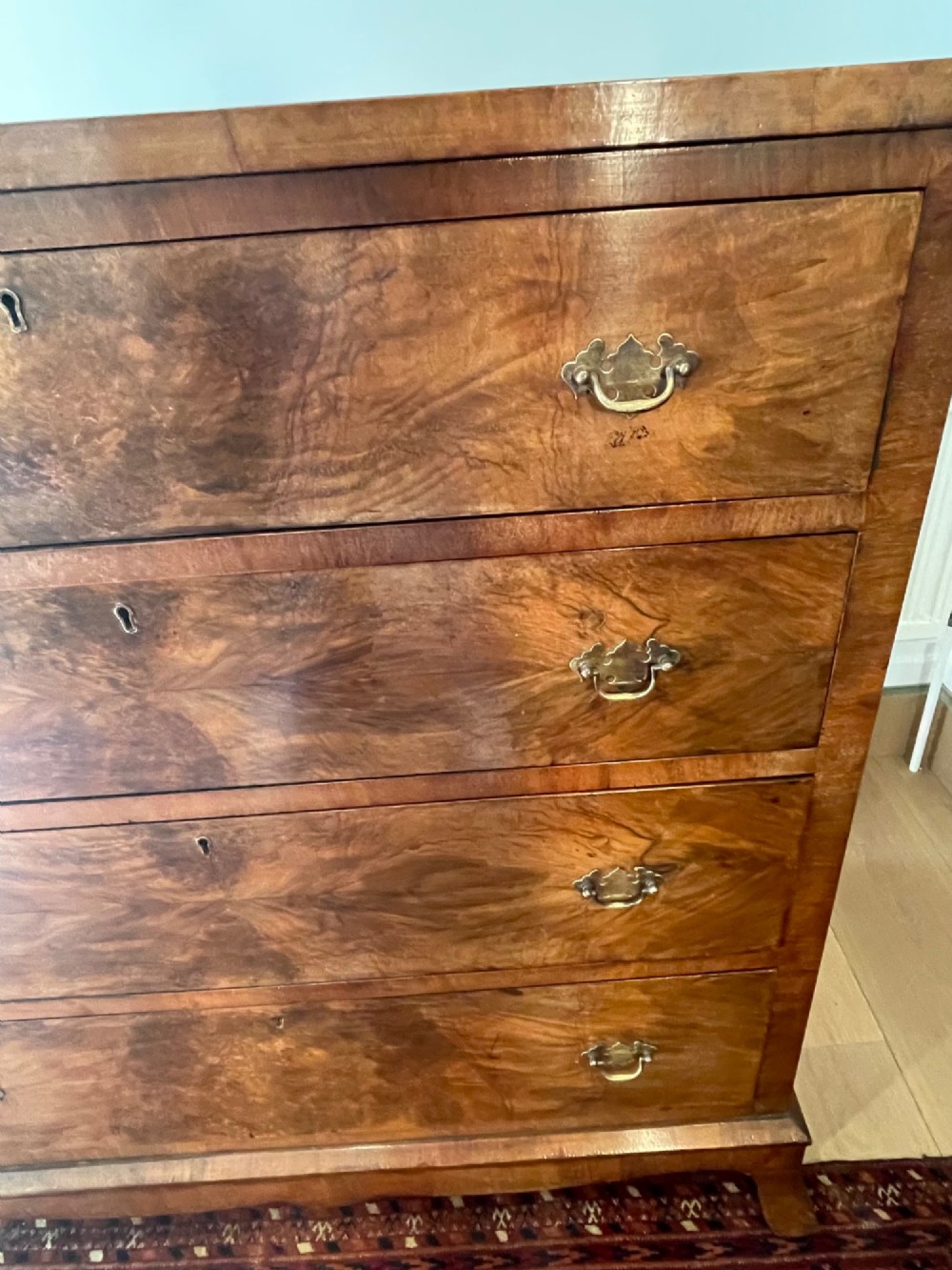 A George V walnut chest of drawers featuring four drawers with figured veneer fronts, brass drop handles, and bracket feet. View XI