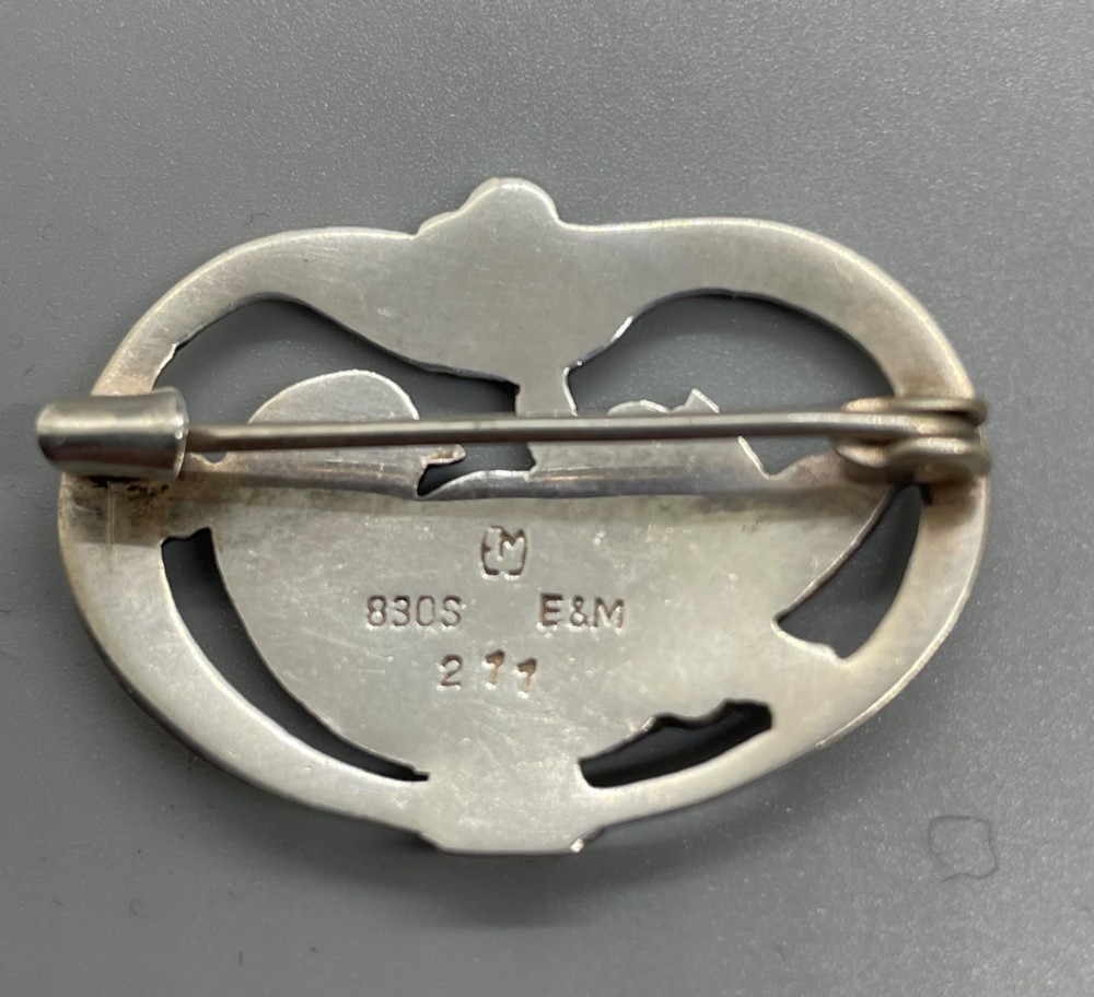 An oval sterling silver brooch depicting a bird in relief surrounded by stylised leaves and silver beads. View III