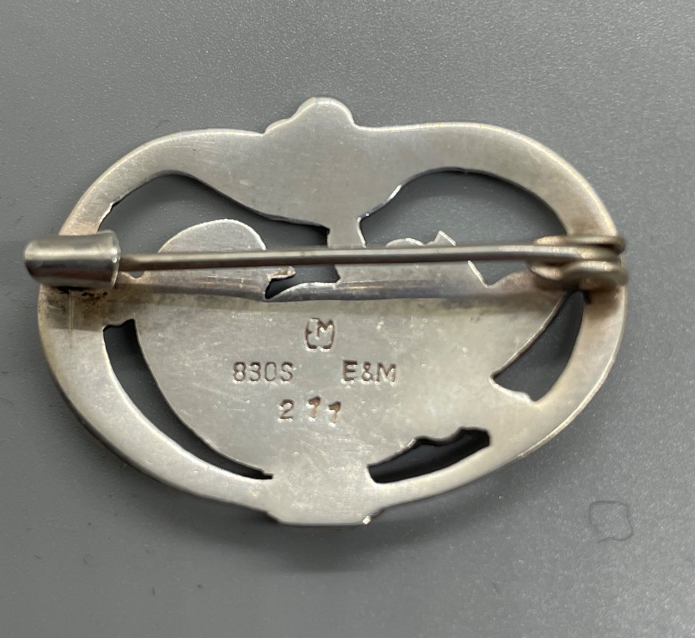 An oval sterling silver brooch depicting a bird in relief surrounded by stylised leaves and silver beads. View IV