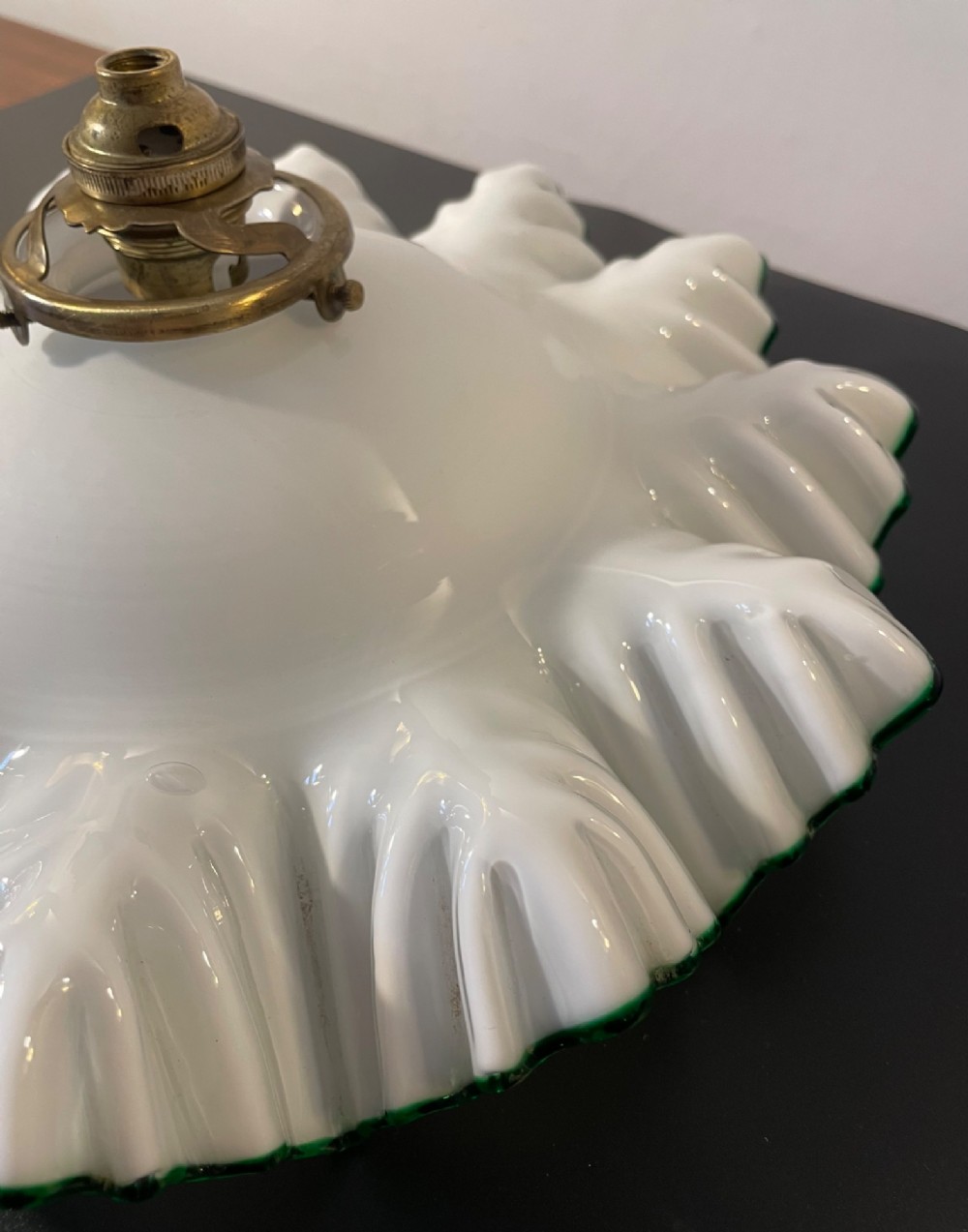 A white opaline glass lampshade with a fluted frilled edge trimmed in green glass, mounted with a brass top fixture. View V