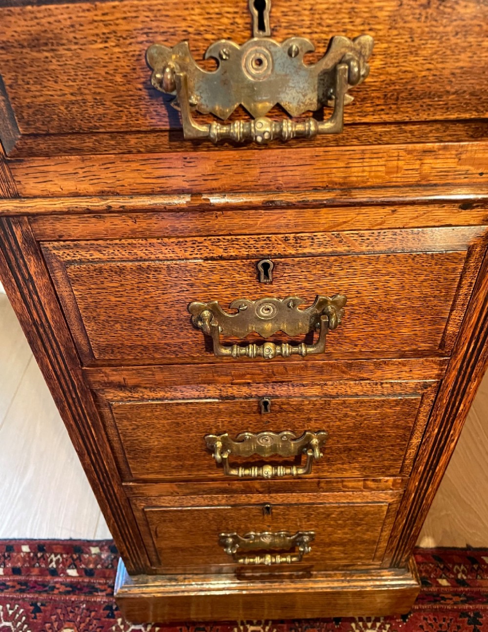 A Victorian oak pedestal desk featuring a gold-tooled leather writing top, nine drawers, and brass handles on a plinth base. View XII