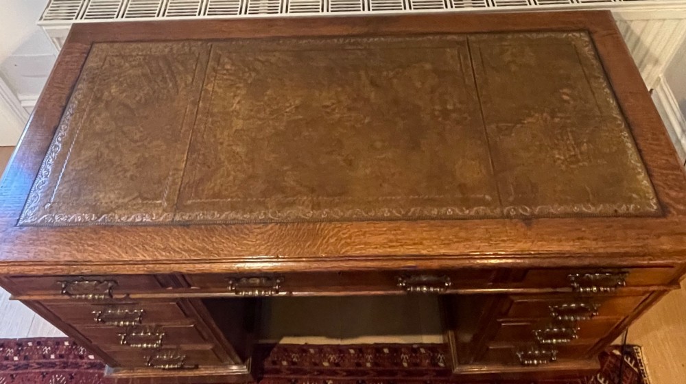 A Victorian oak pedestal desk featuring a gold-tooled leather writing top, nine drawers, and brass handles on a plinth base. View XIII