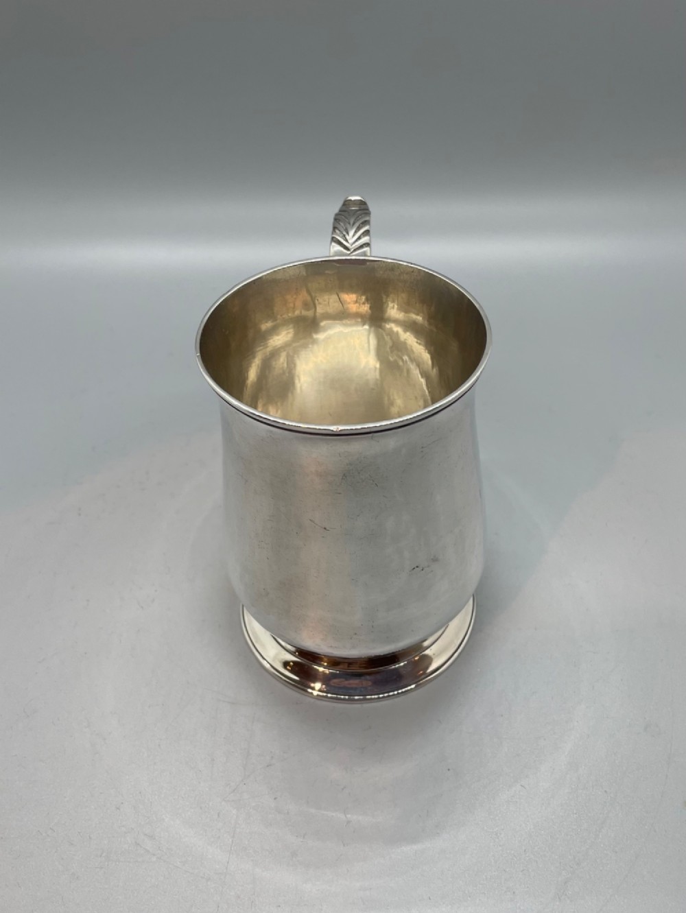 A Georgian sterling silver baluster-shaped mug featuring a leaf-capped double-scroll handle and a stepped circular base. View II
