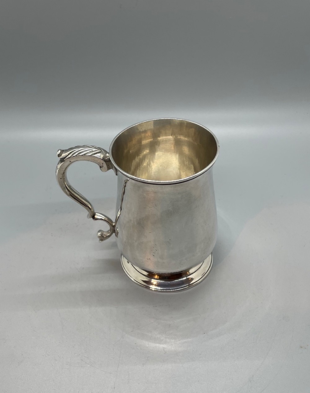 A Georgian sterling silver baluster-shaped mug featuring a leaf-capped double-scroll handle and a stepped circular base. View III
