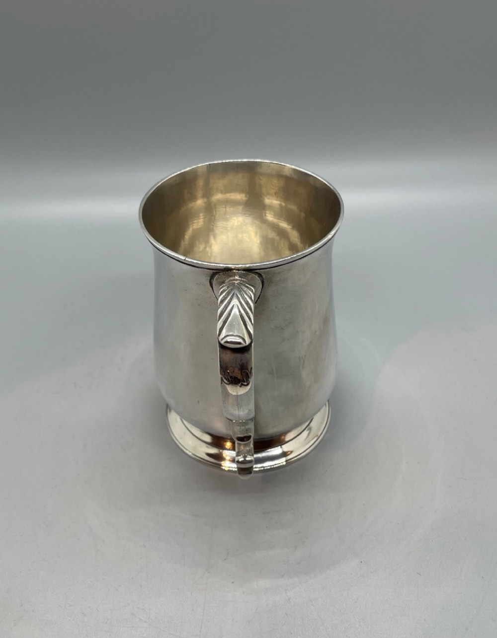A Georgian sterling silver baluster-shaped mug featuring a leaf-capped double-scroll handle and a stepped circular base. View IV