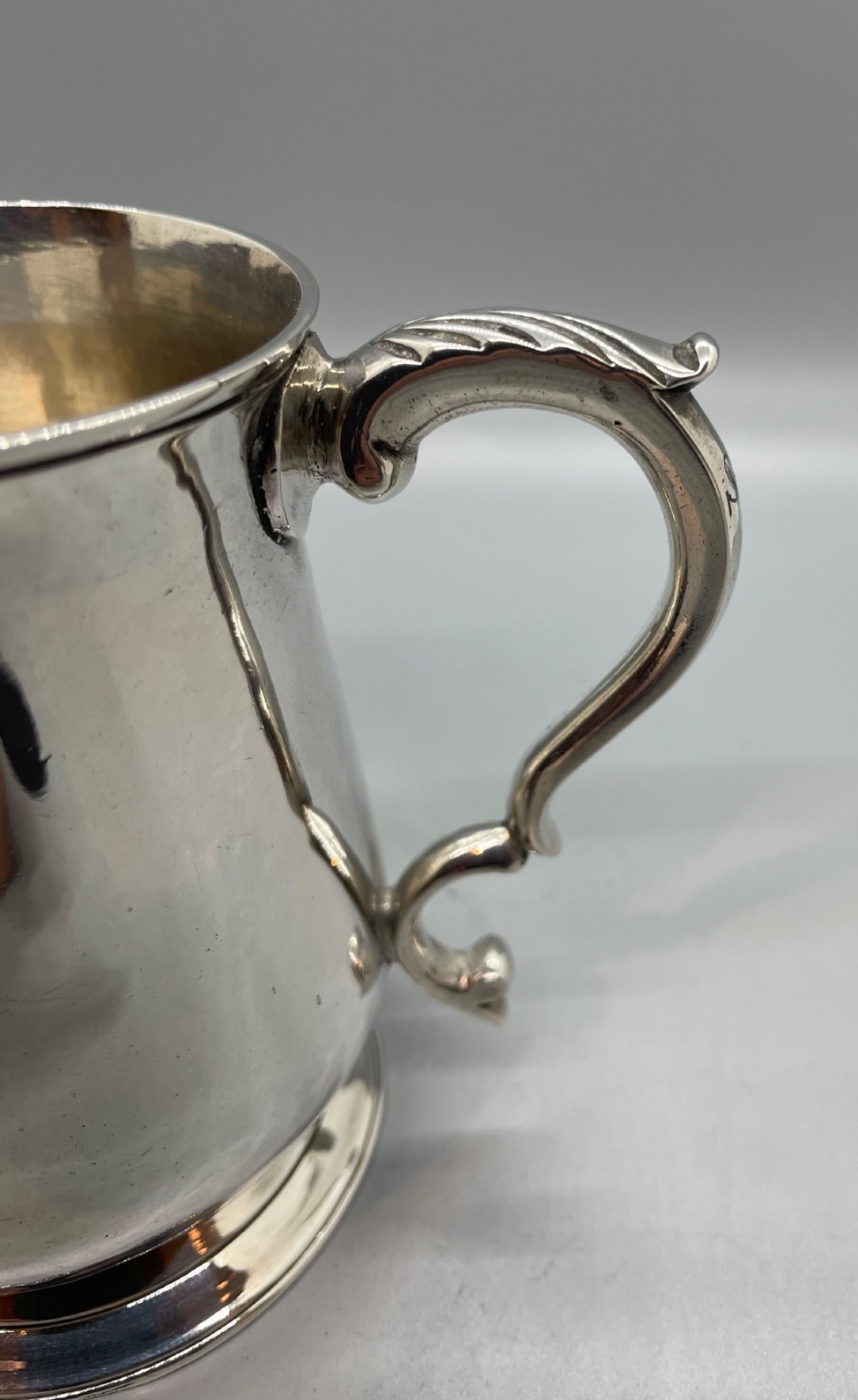A Georgian sterling silver baluster-shaped mug featuring a leaf-capped double-scroll handle and a stepped circular base. View VI