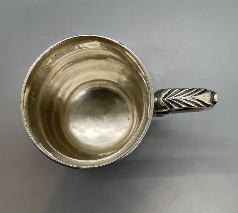 A Georgian sterling silver baluster-shaped mug featuring a leaf-capped double-scroll handle and a stepped circular base. View VII